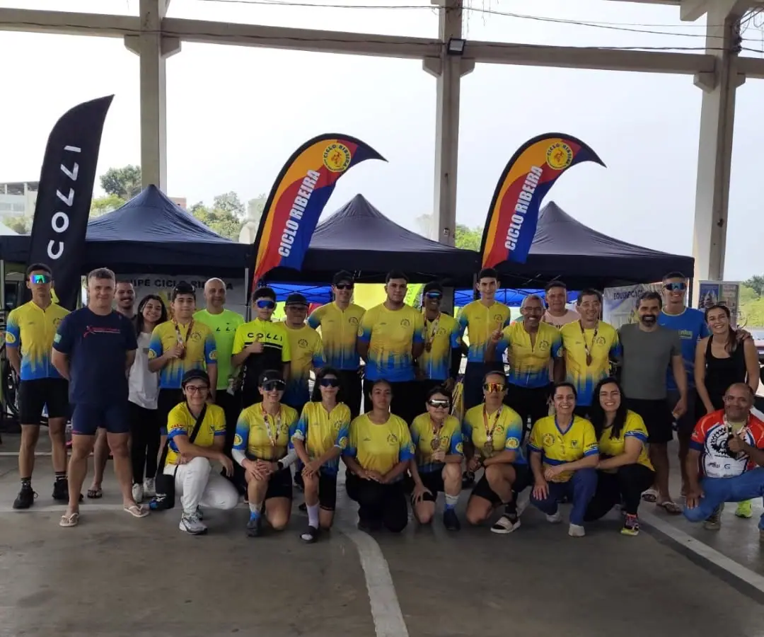 Equipe Ciclo Ribeira reunida em evento de ciclismo, com as bandeiras da loja