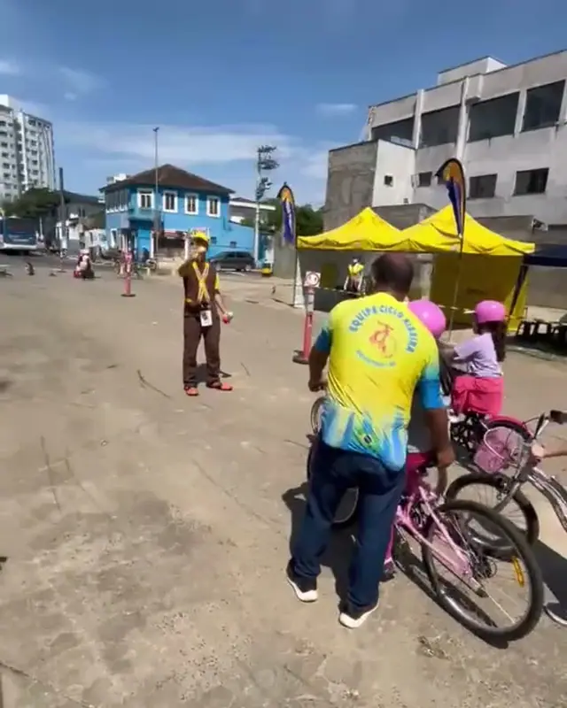 Integrante da Ciclo Ribeira ajudando crianças no circuito de bike da Semana do Trânsito